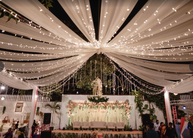 White draped canopy over a floral stage at night