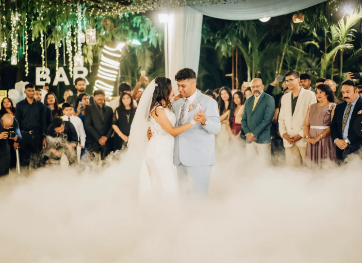 Bride and groom first dance with fog effect near a lit bar sign