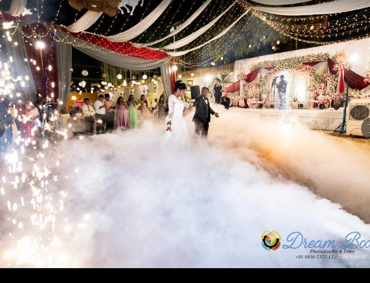 Couple's first dance in low fog with sparklers, red and white floral stage behind