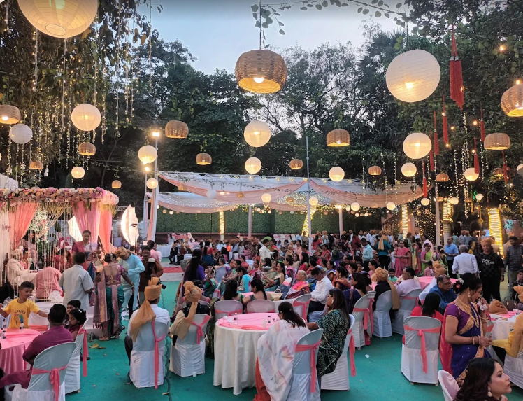 Guests seated under a canopy of paper lanterns and fairy lights at Blossoms Lawn during a wedding reception