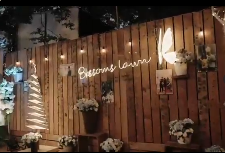 Rustic wooden photo wall backdrop with neon signage and florals
