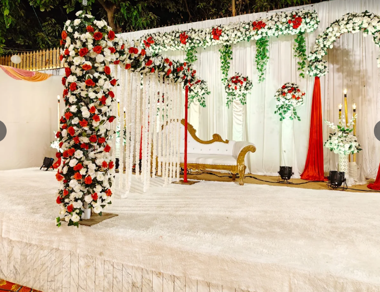 Red and white floral stage decor with golden seating